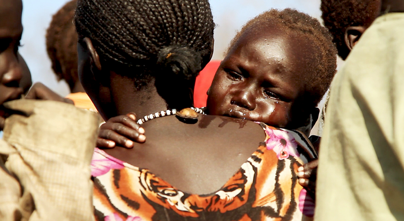 An exhausted young mother carrying her sick child. (Photograph: © Viktor Pesenti)