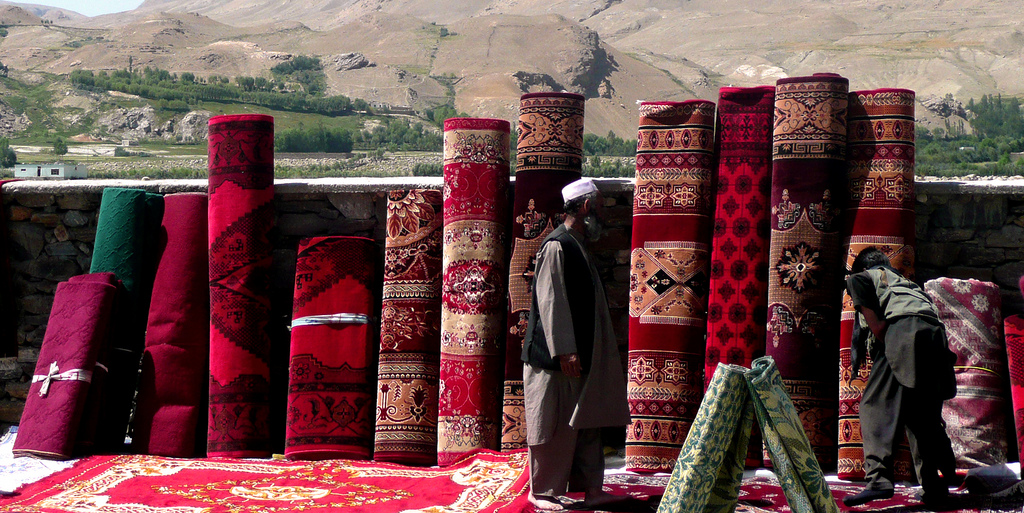 A natural salesman, the boy displays a collection of his finest Afghan carpets against the stunning backdrop of the Pamir Mountains.