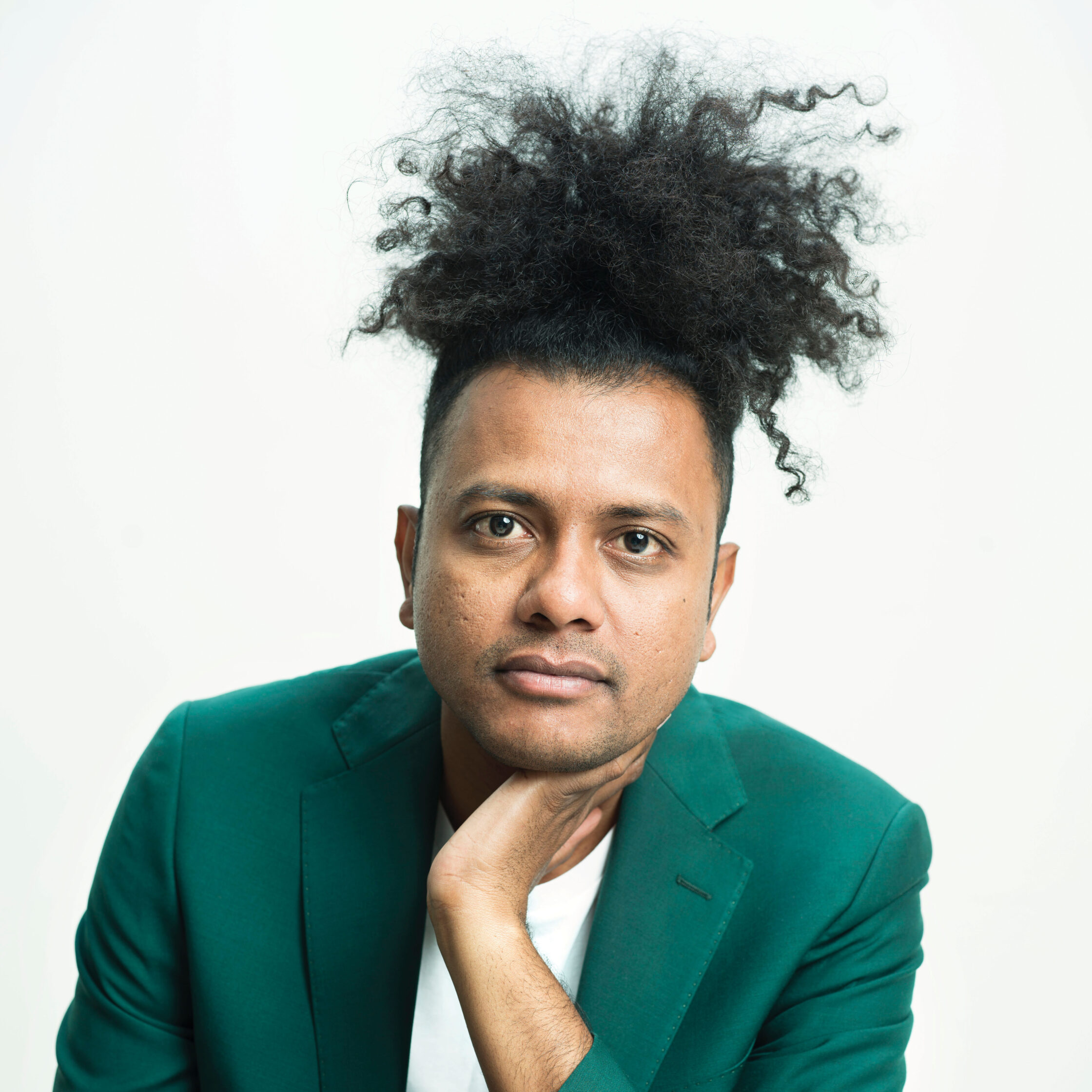 Author Suraj Milind Yengde wears a green suit jacket against a white background